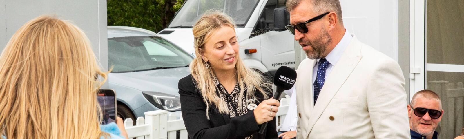 A member of the marketing team interviewing people on a raceday at Newcastle Racecourse