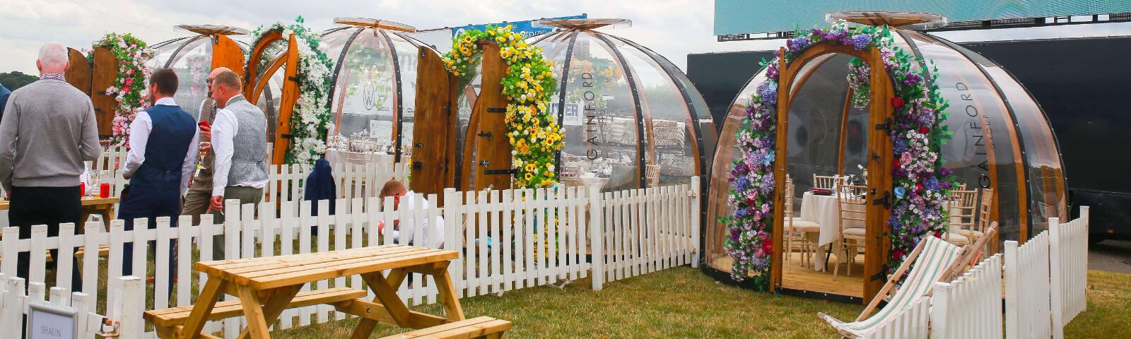 Luxury hospitality pod with flower entrance, picket fence and bench.